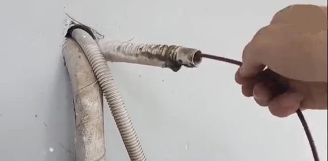 Dùng dây điện chọc vào ống thoát nước thải máy lạnh để thông cho sạch